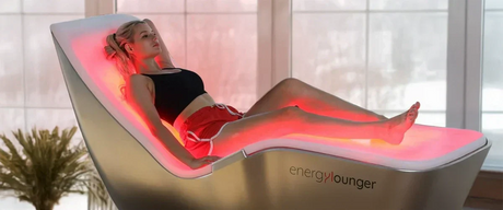 A woman lying with her eyes closed on the EnergyLounger red light therapy lounger/bed.
