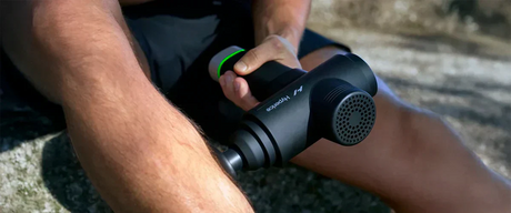 A man using a Hypervolt massage gun on his calf.