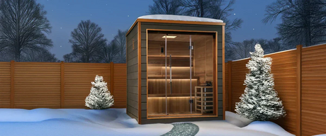 Golden Designs brand of sauna outside in the corner of a snowy backyard at night