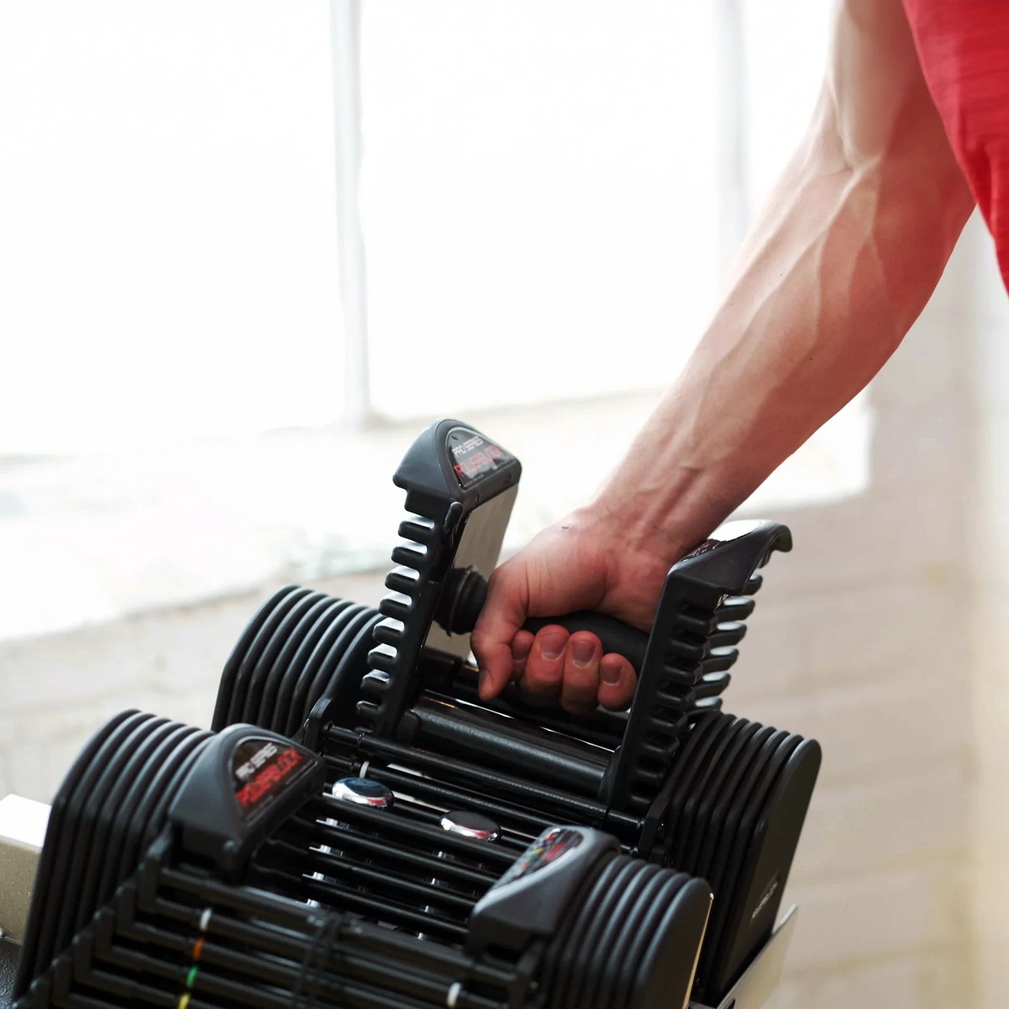 A man removing the handle from a PowerBlock Pro 50 Dumbbell