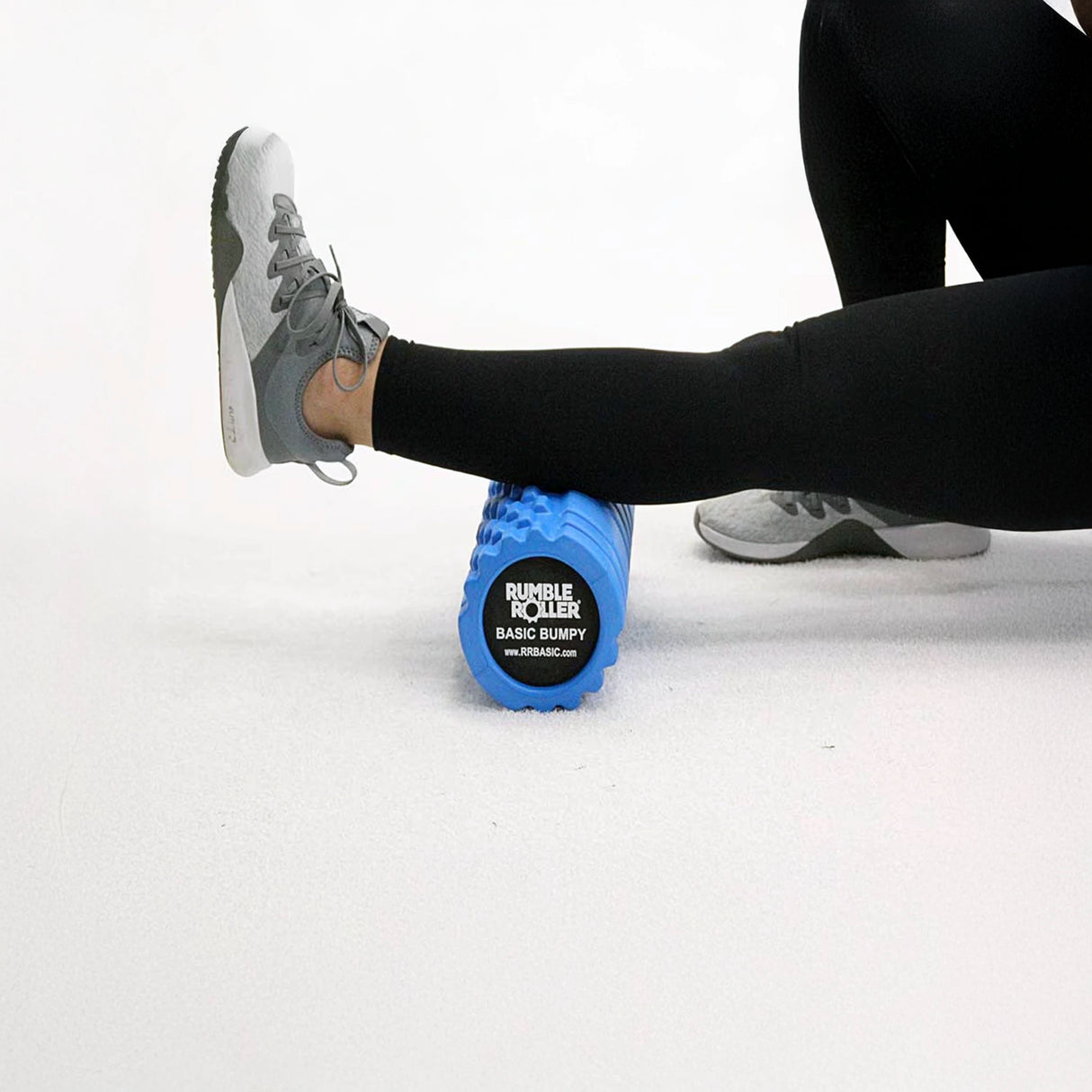 Woman rolling calf on blue uneven foam roller by Rumble Roller