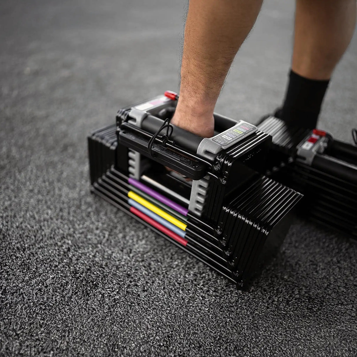 A man picking up a PowerBlock Elite USA 90 dumbbell handle from the floor