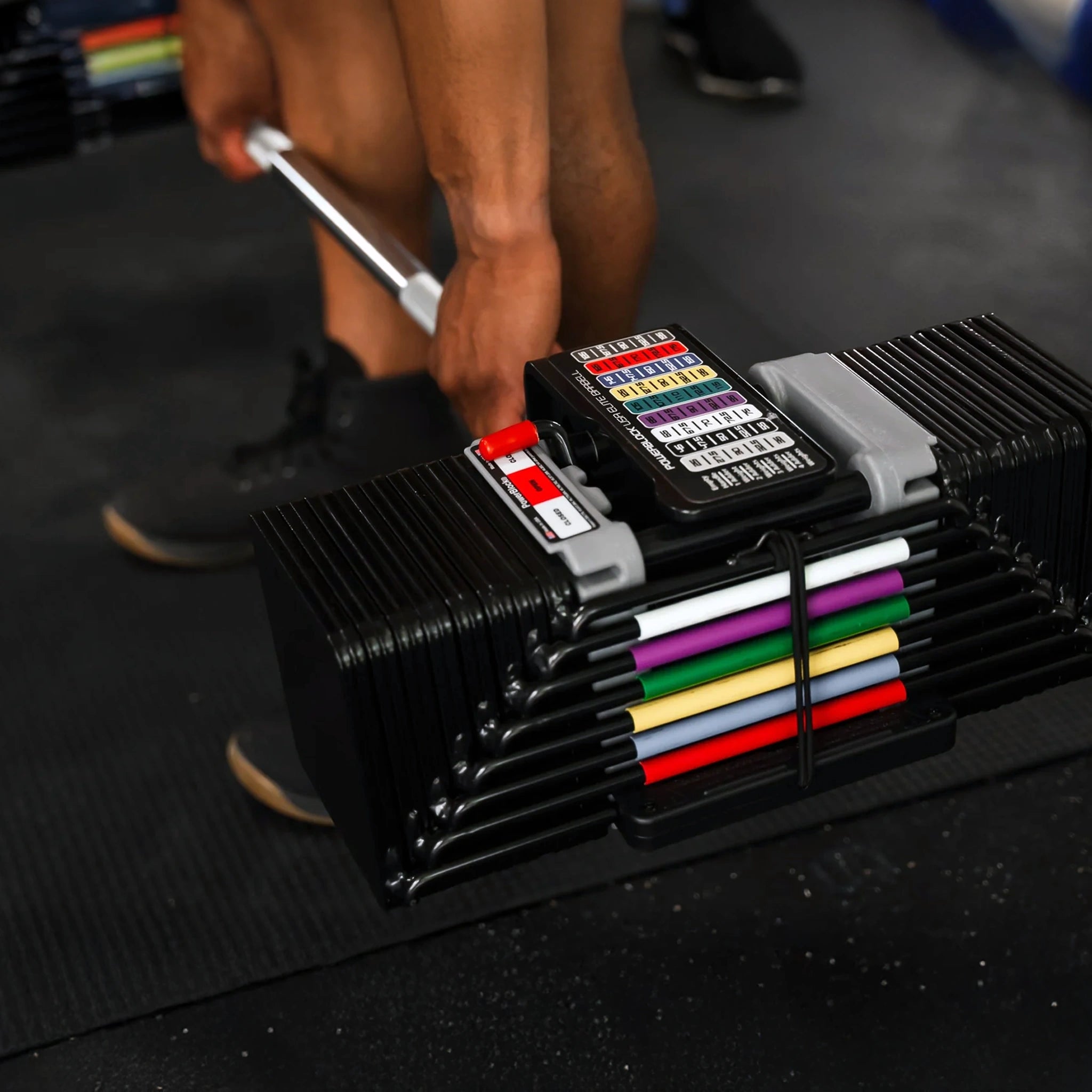 A man about to deadlift a pair of PowerBlock Elite USA 90 Expandable Dumbbells attached to a straight PowerBlock barbell