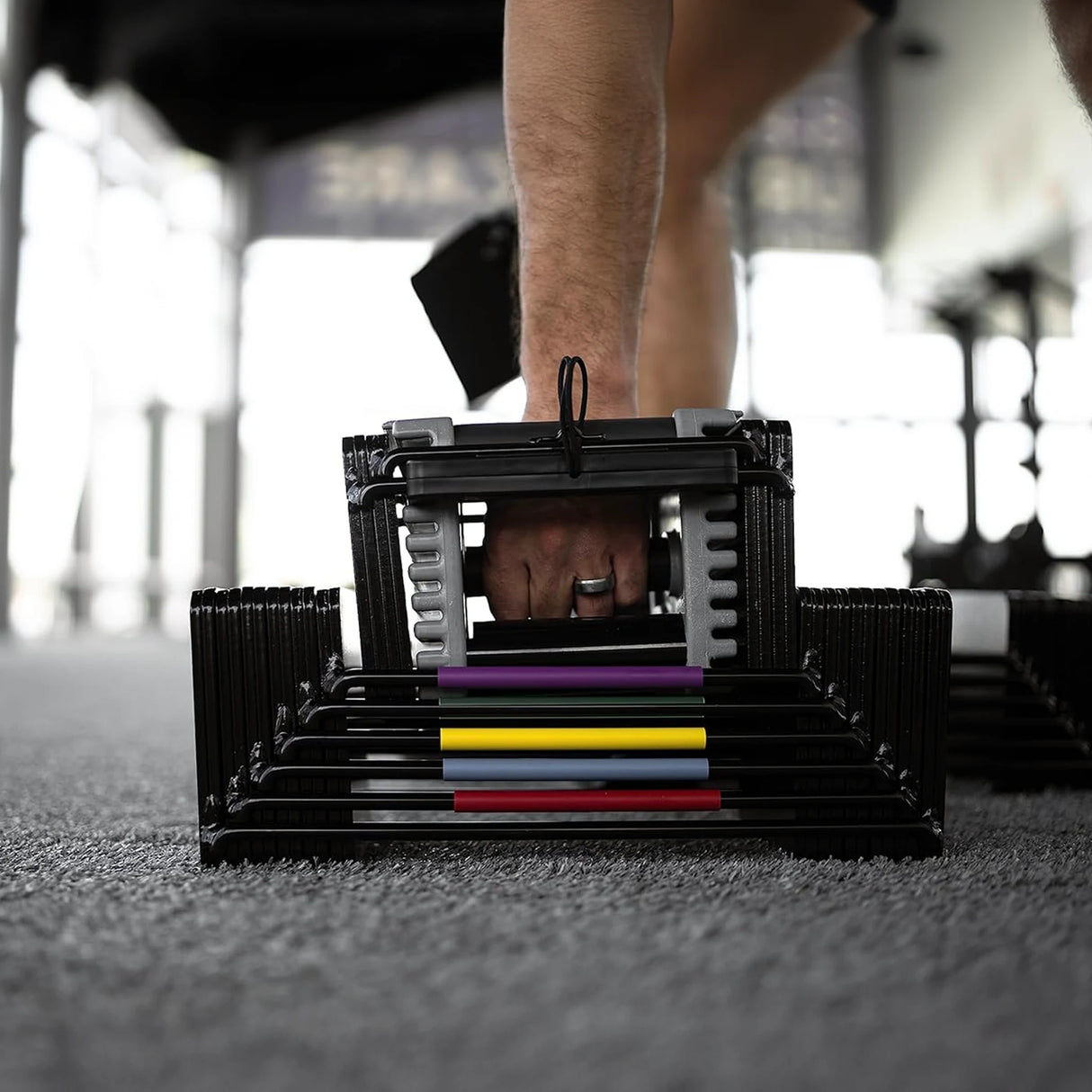 A man picking up a PowerBlock Elite USA 90 dumbbell handle from the floor