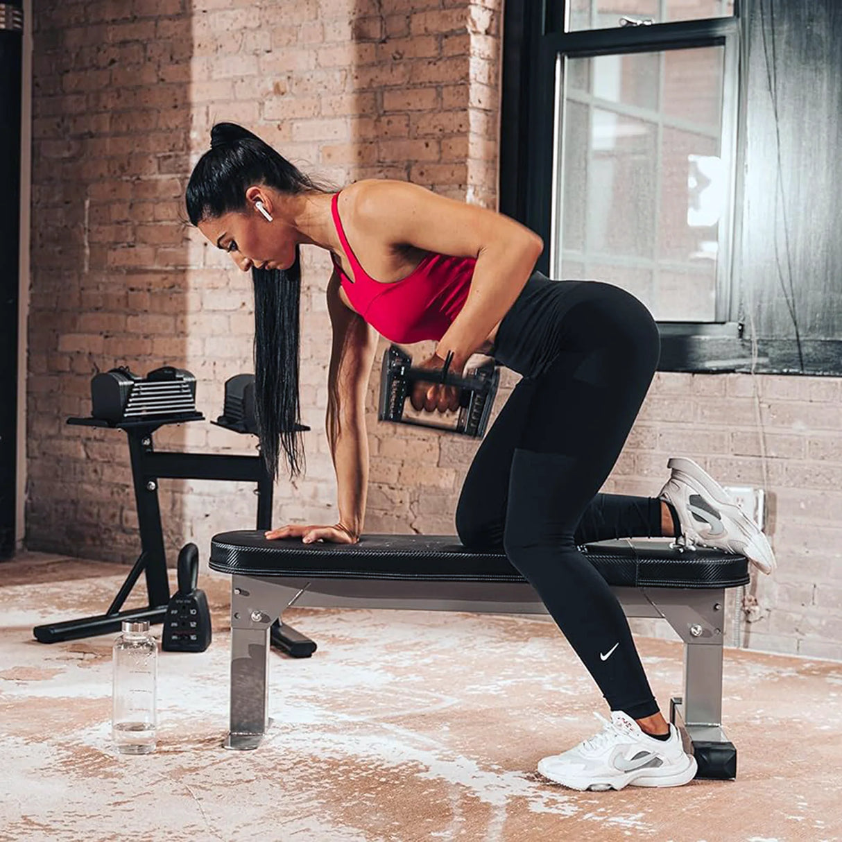 A woman doing single arm dumbbell rows on a PowerBlock Fold Up Portable Travel Bench