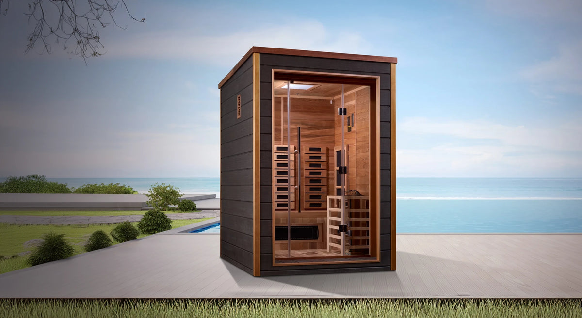 Nora model hybrid full spectrum infrared traditional steam sauna made by Golden Designs with a 3 person capacity which is constructed from Canadian red cedar on the interior and dark all weather composite on the exterior and is built for outdoor use on a deck overlooking the ocean