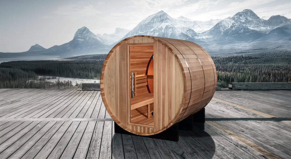 Golden Designs Zurich model barrel shaped sauna with a 4 person capacity which is built for outside use photographed on a deck overlooking a river and snow-capped mountains