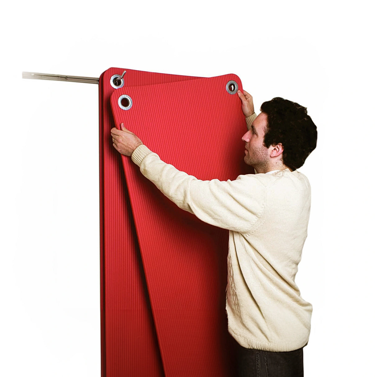 Red exercise mat with eyelets by CanDo being hung up on wall storage prongs