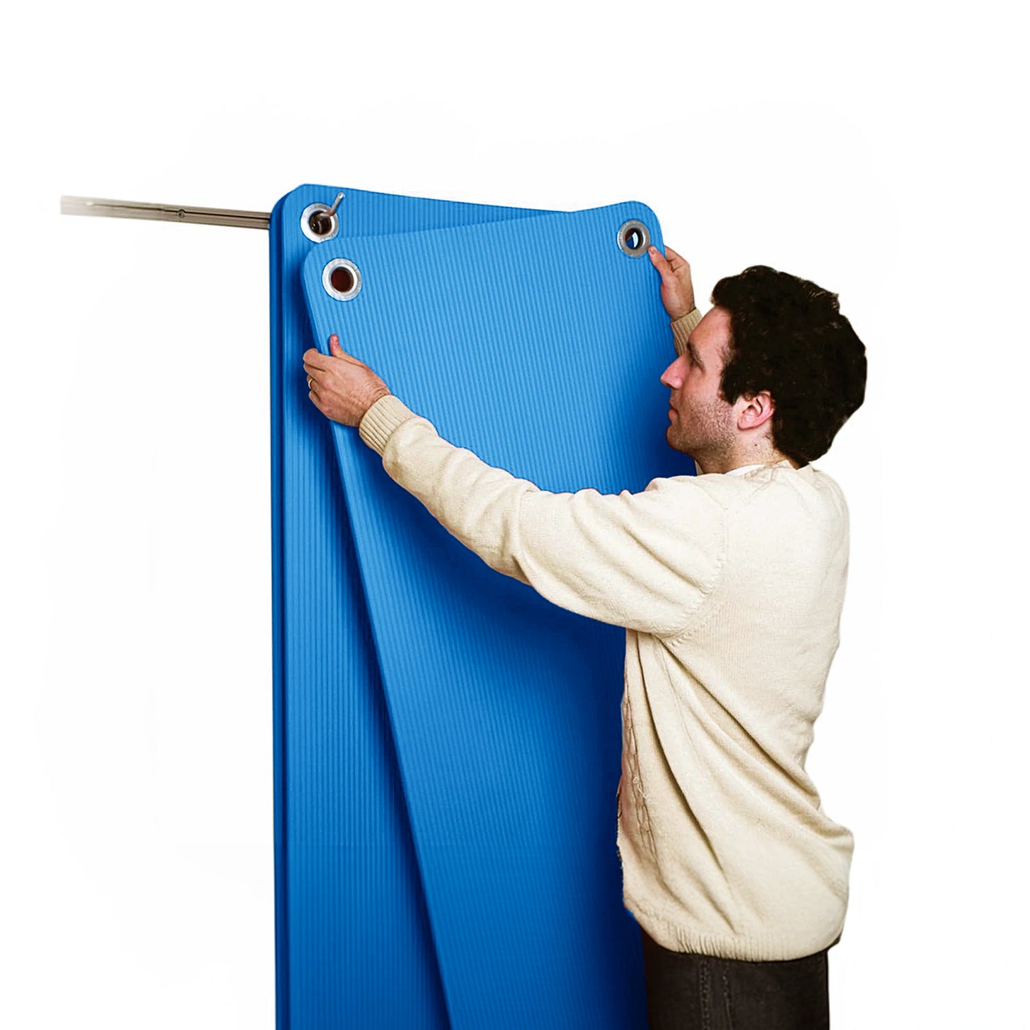 Blue exercise mat with eyelets by CanDo being hung up on wall storage prongs