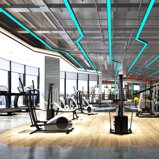 High end futuristic gym with neon blue green lights overhead and new equipment on a light wooden floor