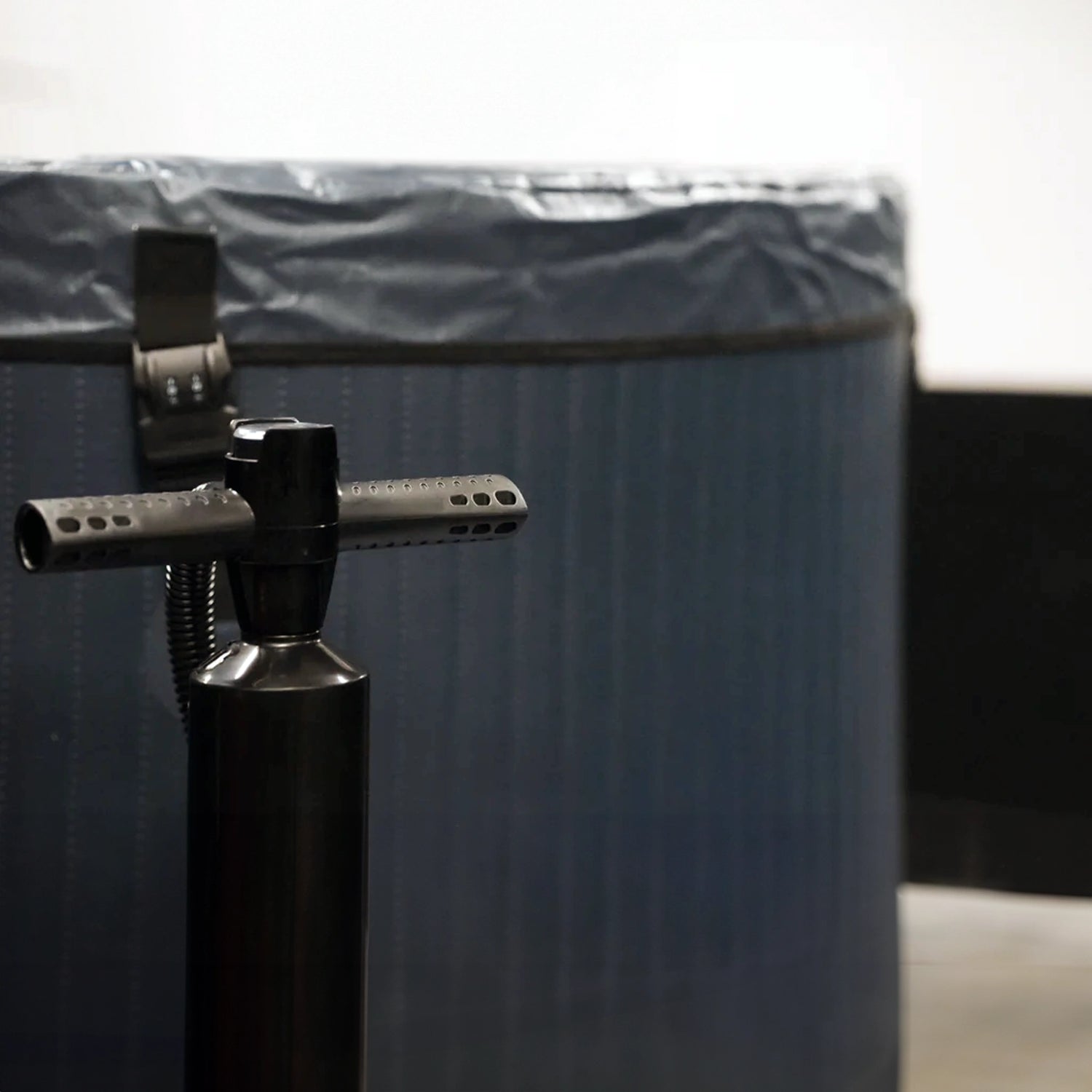 Dark blue inflatable cold plunge tub with a black pump sitting next to it