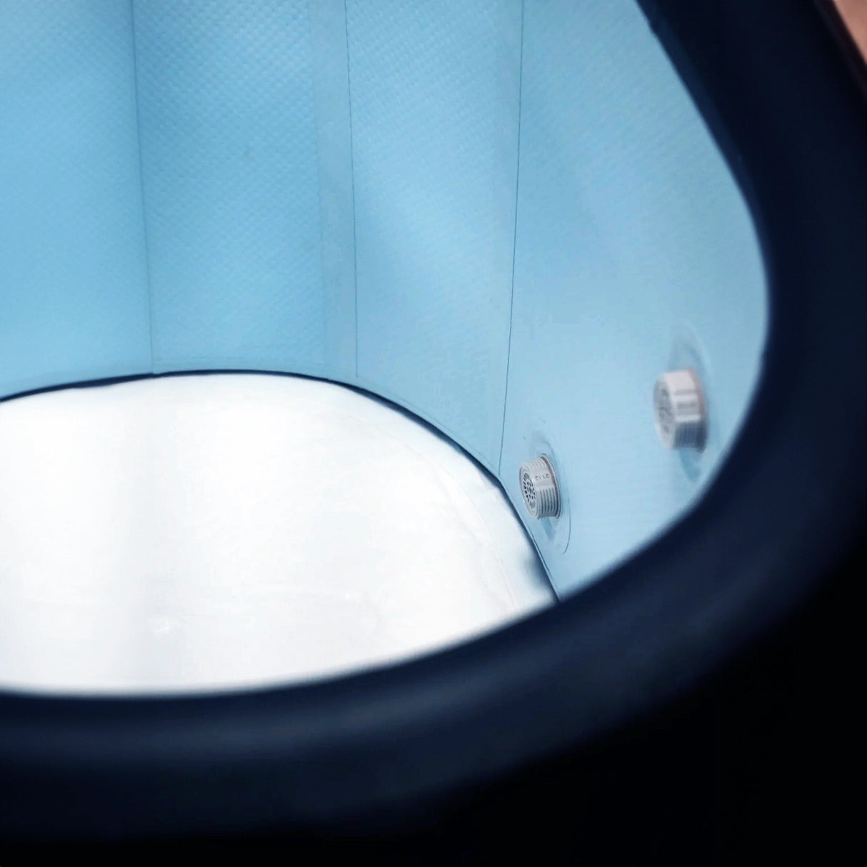 Closeup image of the inside of an inflatable cold plunge with a dark blue exterior, light blue inside walls, and white floor