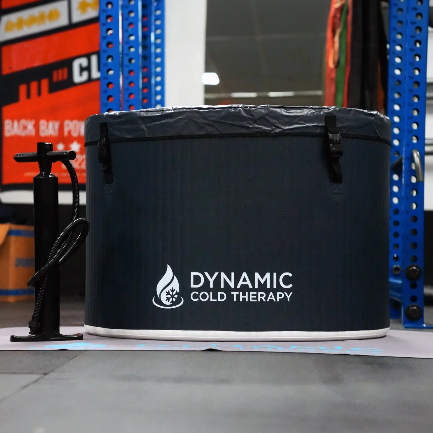 Dark blue inflatable cold plunge tub with a black pump sitting next to it