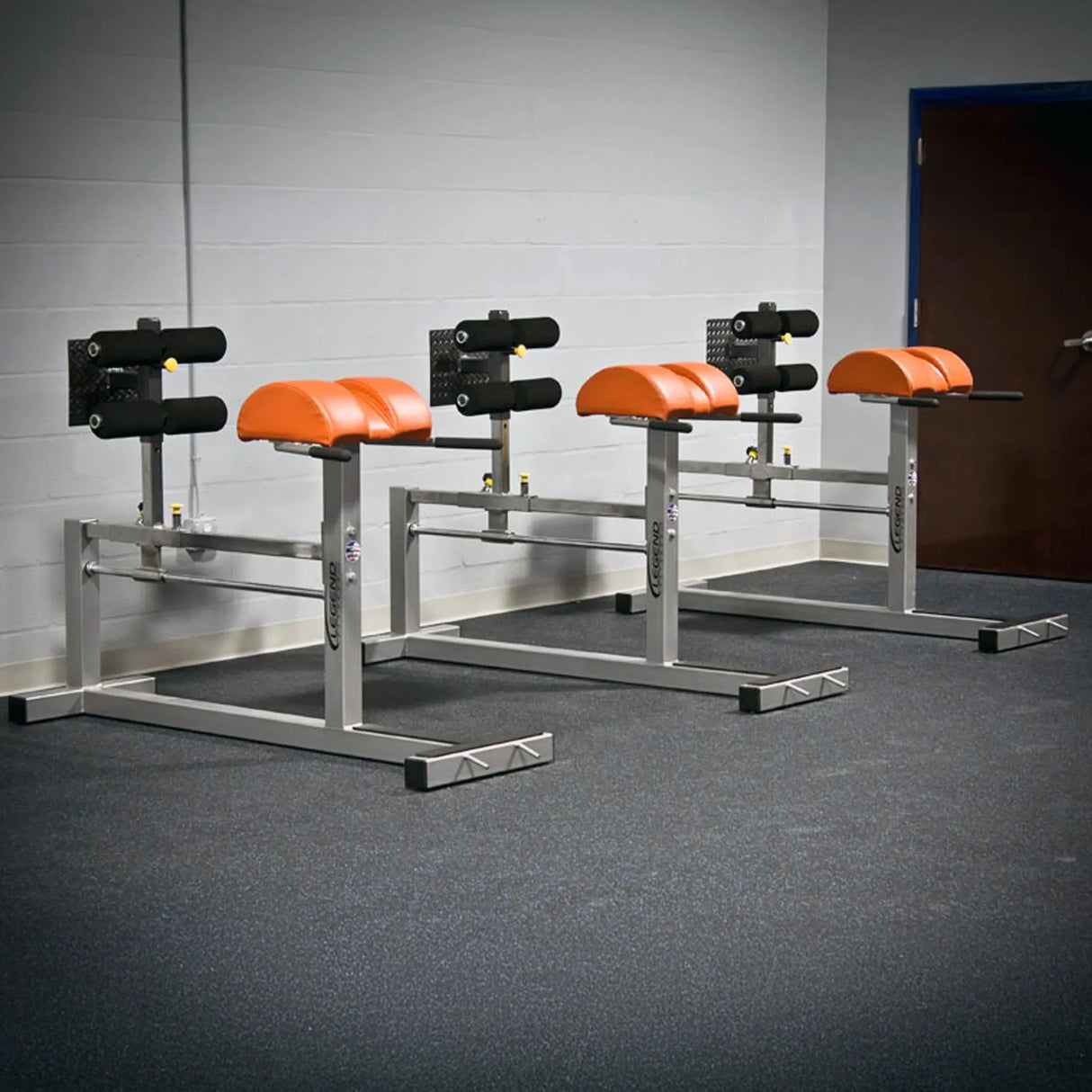 Three silver and red glute ham developer fitness machines in a gym setting