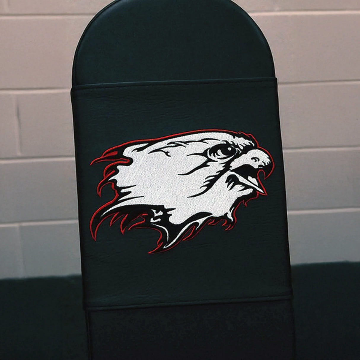 A black gym bench pad with a white and red eagle logo embroidered on it