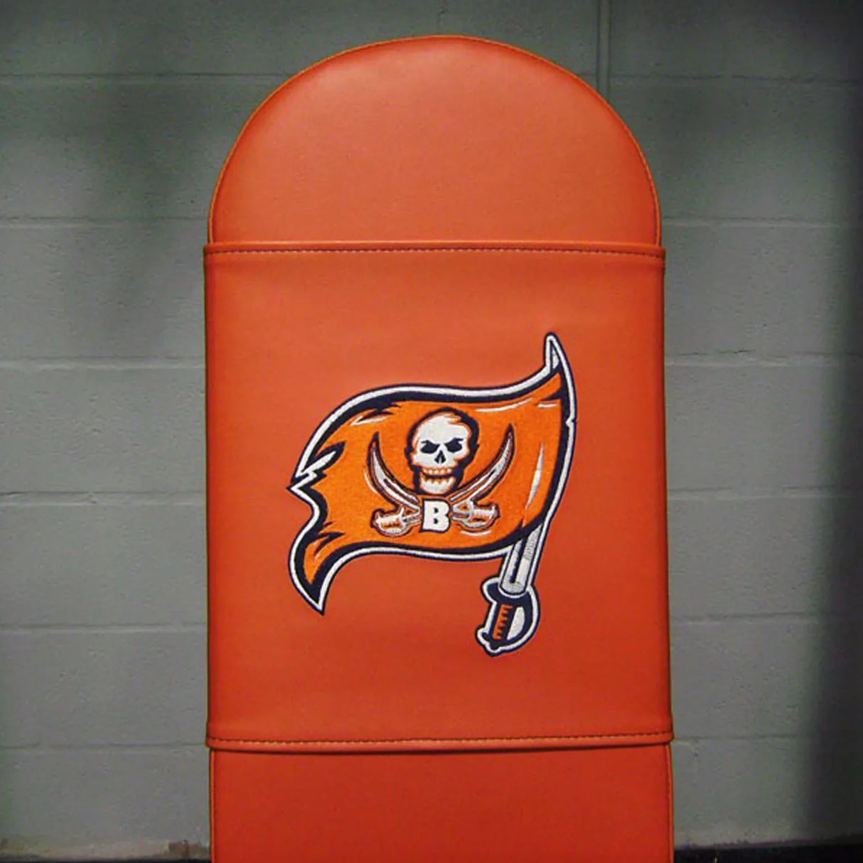 Orange gym bench with a pirate flag logo embroidered on the pad on a gray background