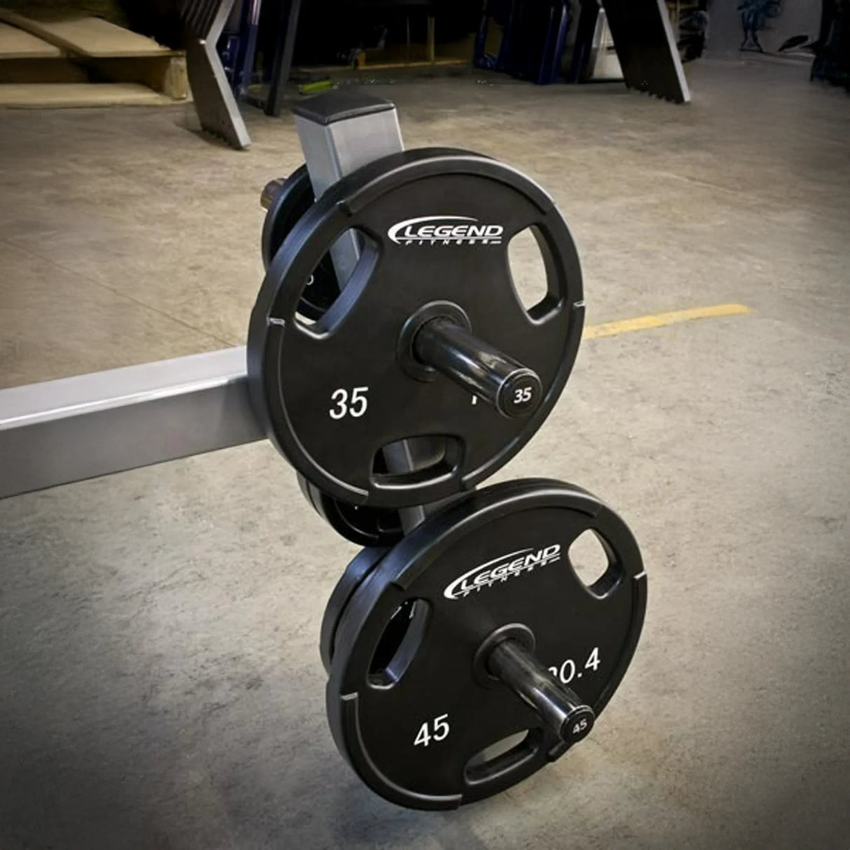 Weight pegs on a gray metal frame holding weight plates on a concrete floor in a gym setting