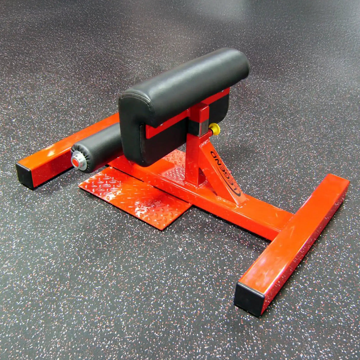 An orange Sissy squat fitness machine with black pads on a black and white gym floor