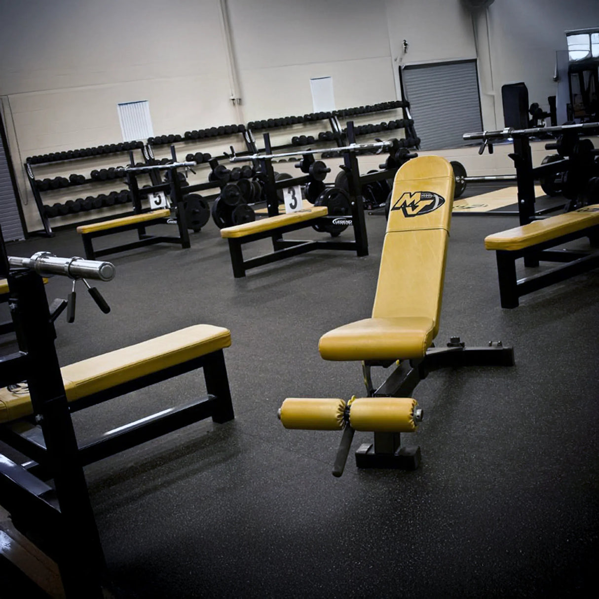 Gym interior with yellow weight bench and equipment.