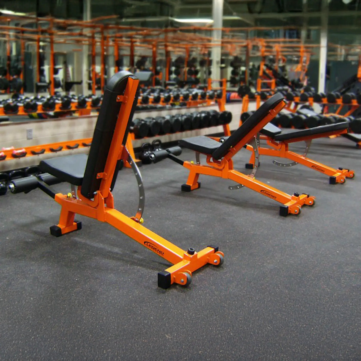 Orange weight bench in a gym setting with multiple benches and equipment.