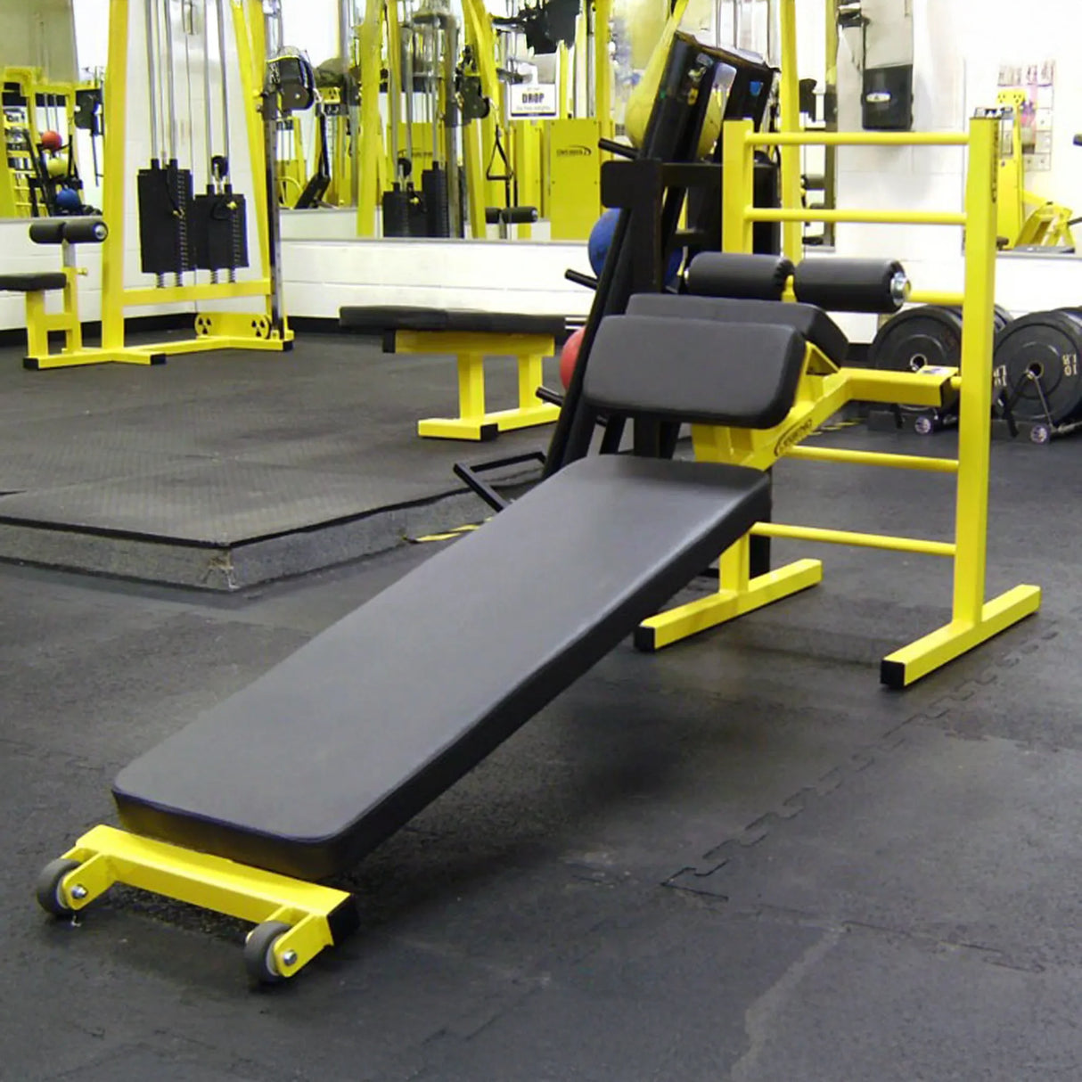 A black and yellow sit up bench in a gym sitting