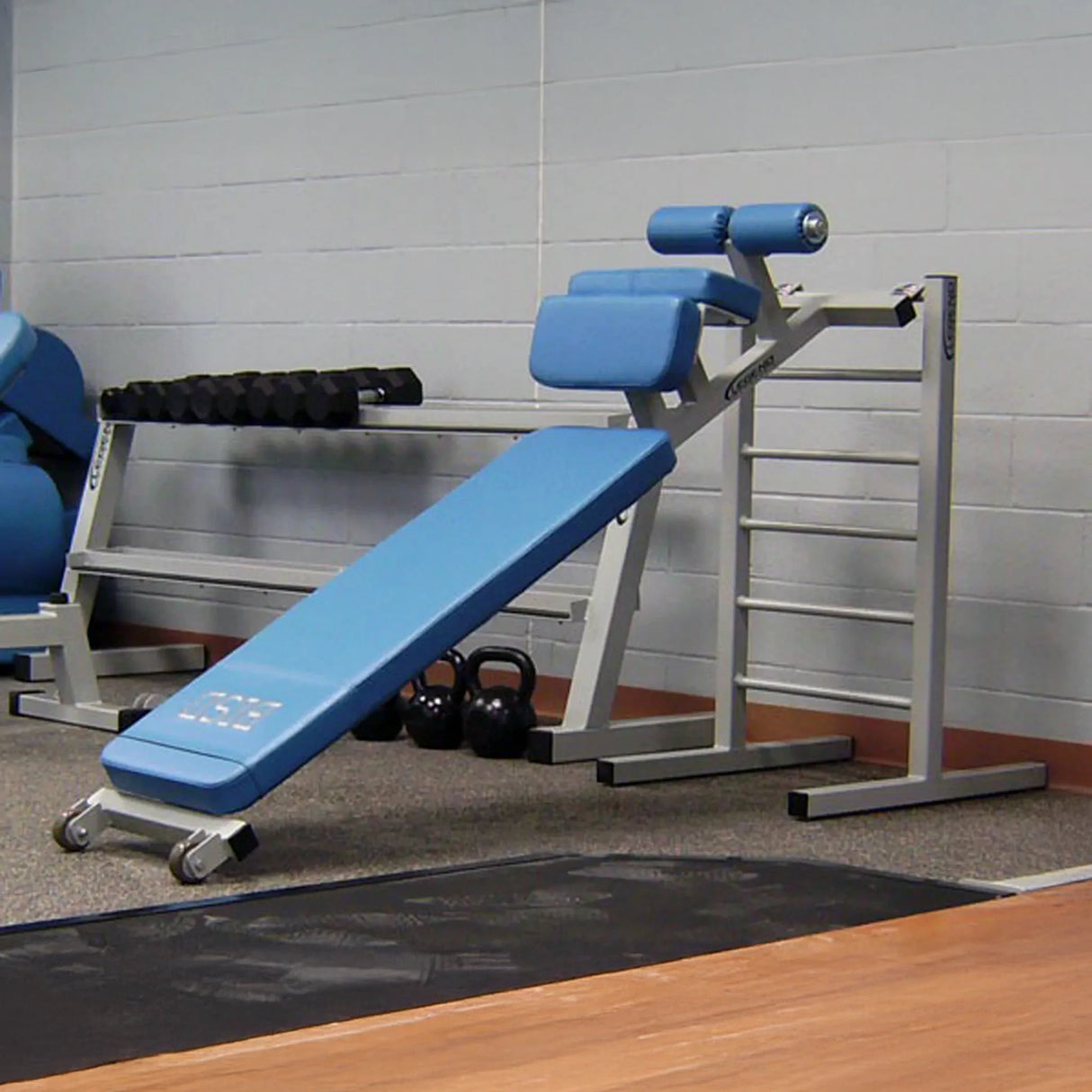 A blue and silver sit up bench in a gym setting