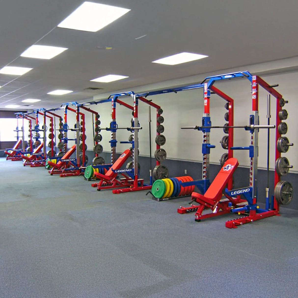 Gym with multiple weight racks and benches arranged in a row.
