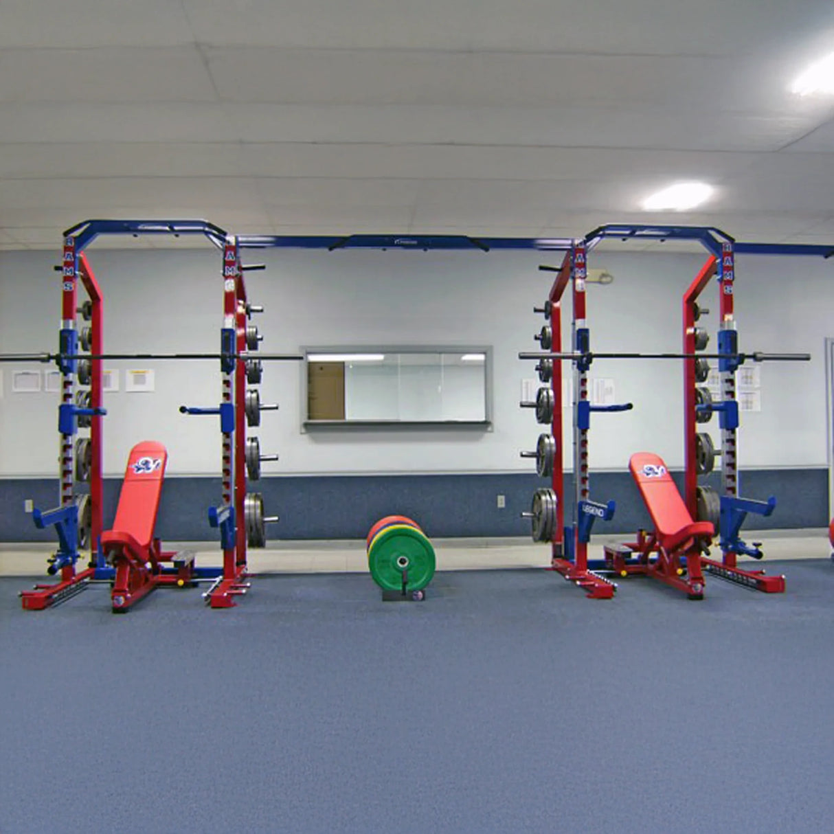Gym with weight lifting equipment including red weight benches and blue weight racks.