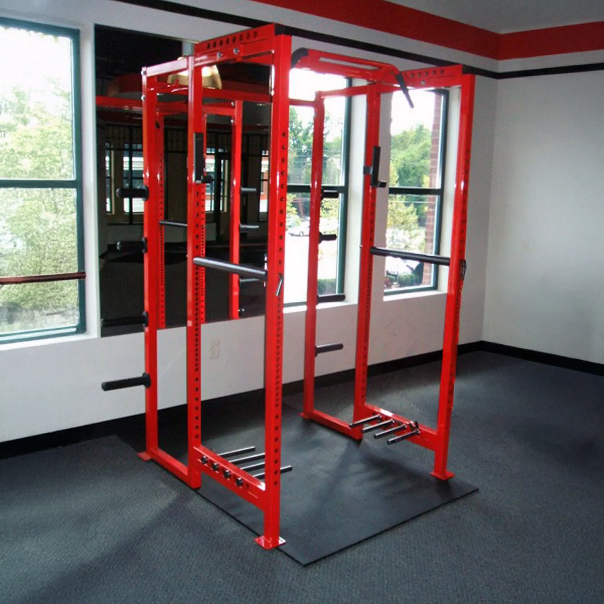 Red fitness power rack in a room with large windows
