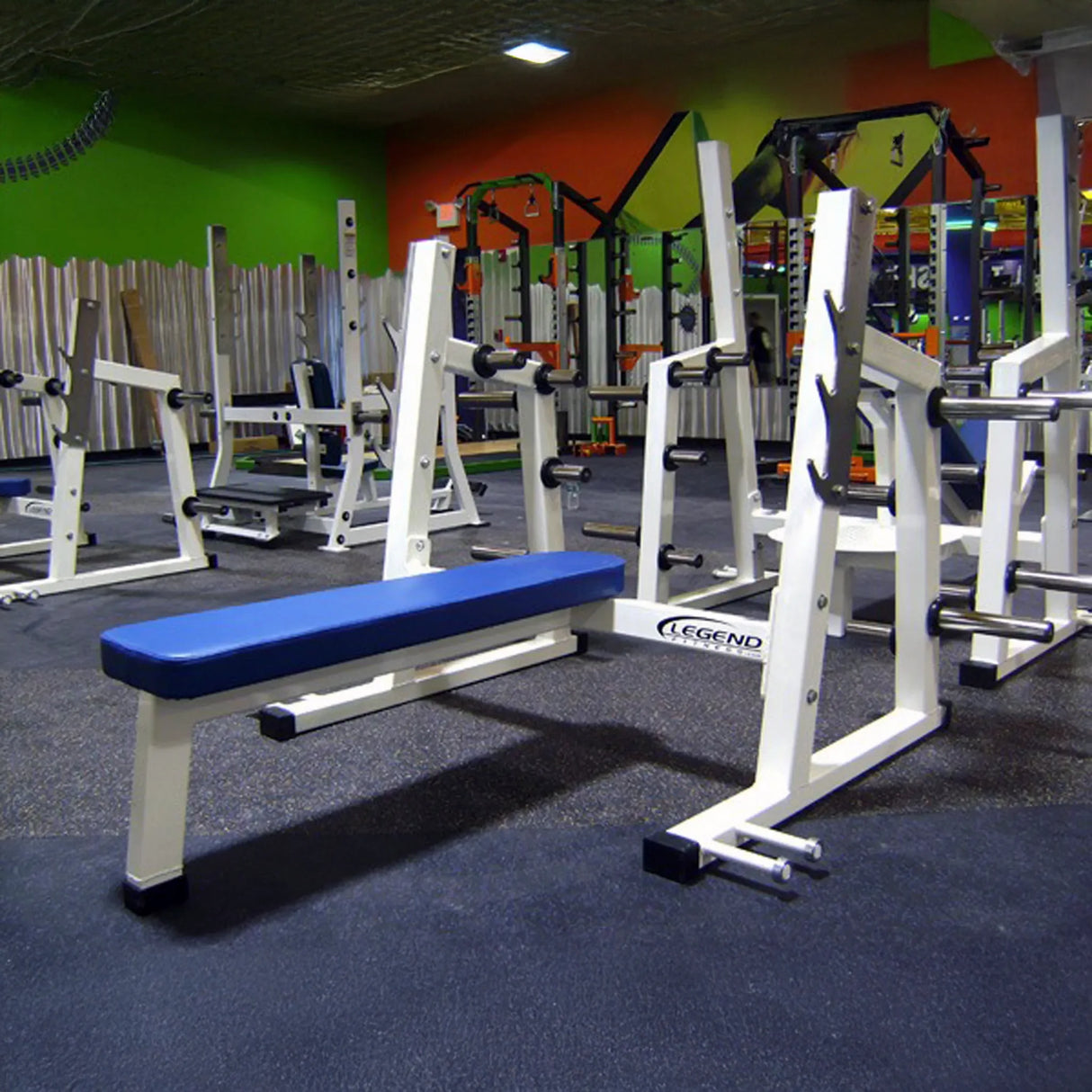 A blue and white Olympic flat bench press in a gym setting