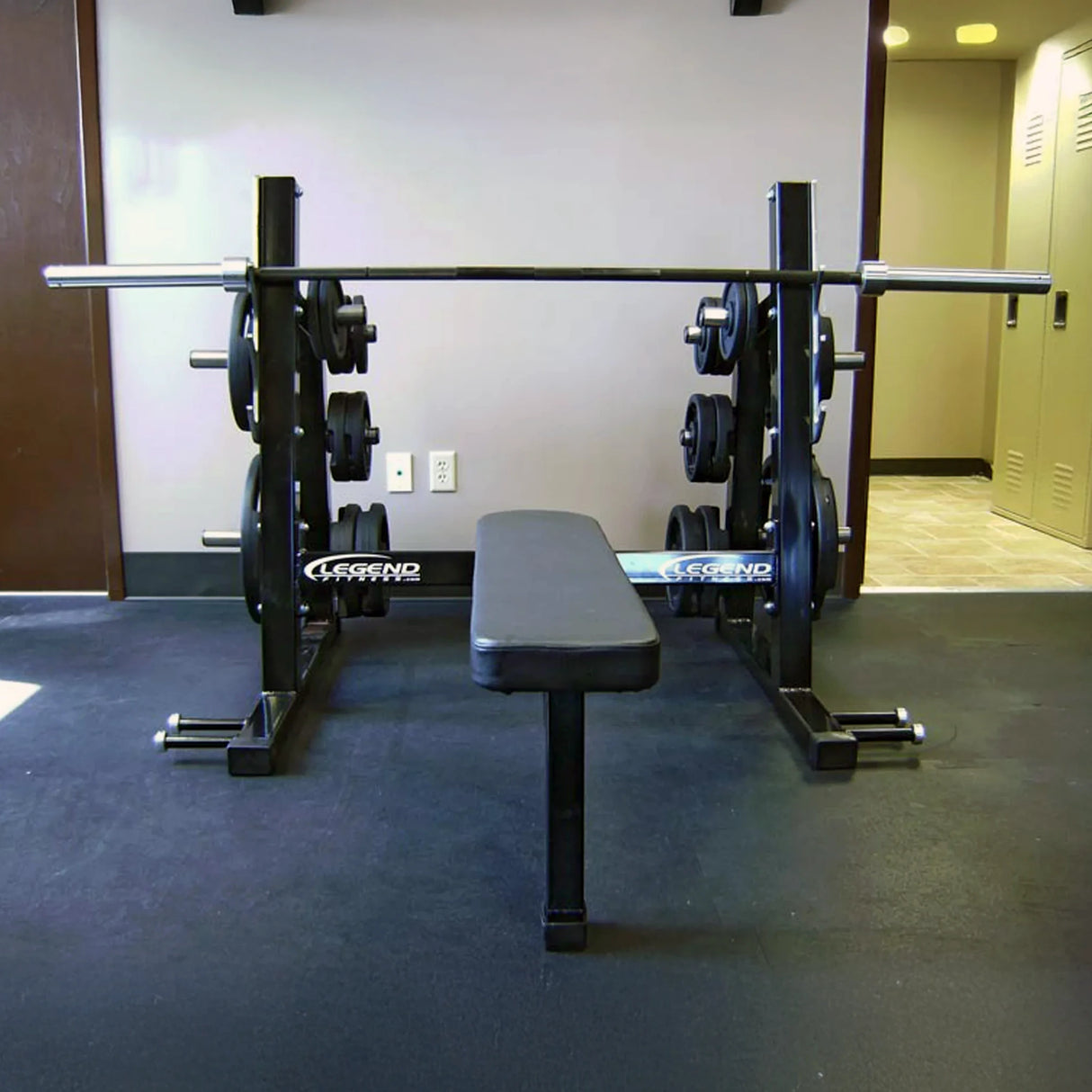 A black Olympic flat bench press on a black floor