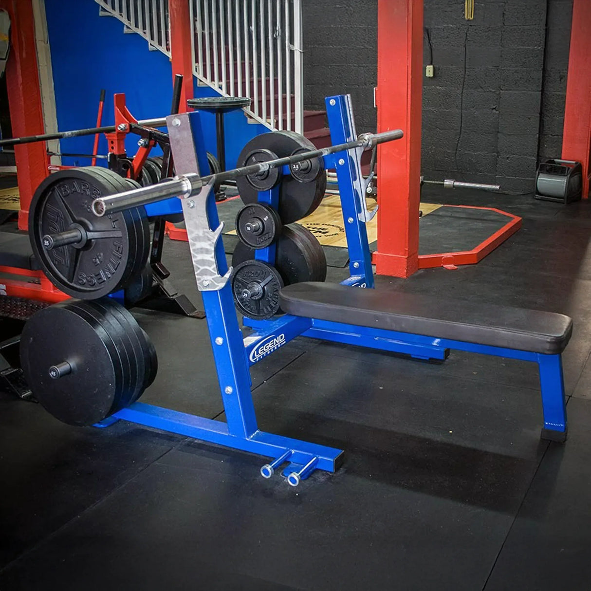 A blue Olympic flat bench press in a gym setting