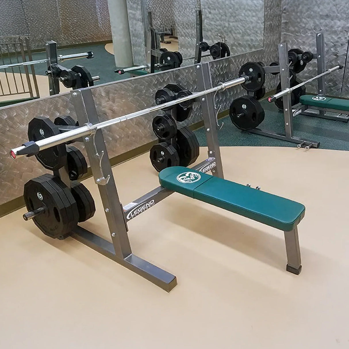 A gray and green Olympic flat bench press in a gym setting