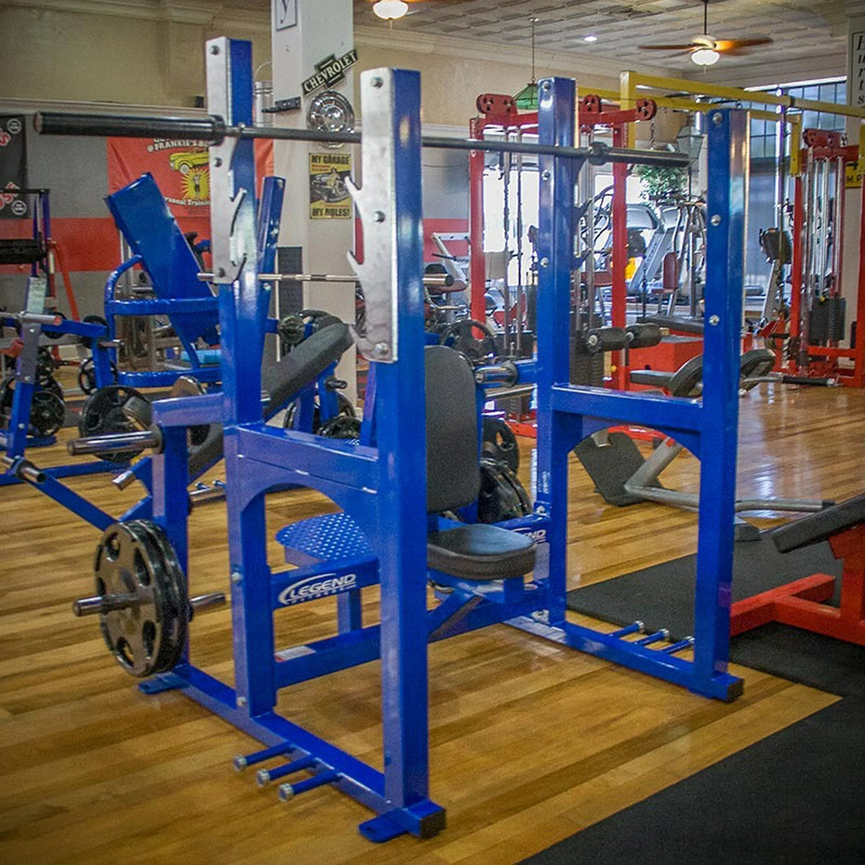 A blue Olympic shoulder press bench in a gym setting.
