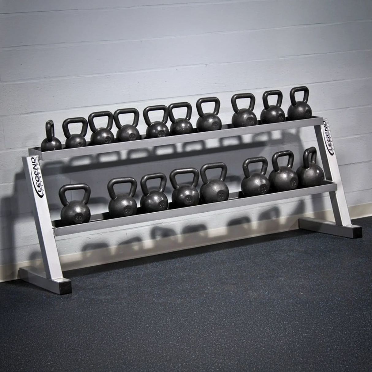 Kettlebell rack with kettlebells on a gray floor against a light gray wall.