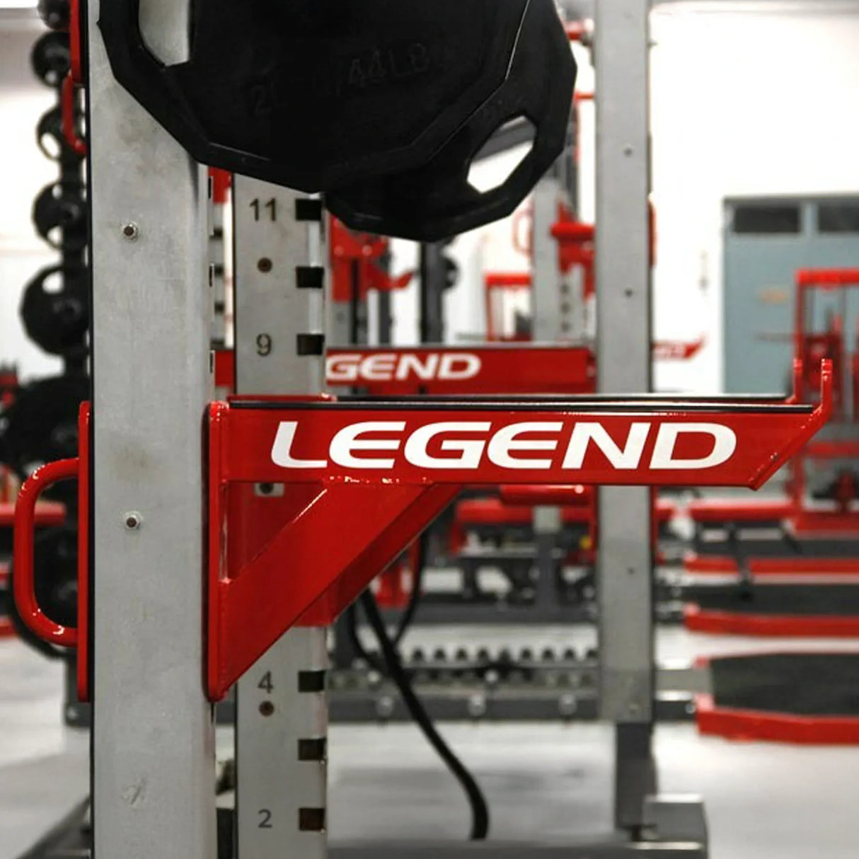 A metal safety arm mounted to a squat rack with 'Legend' branding