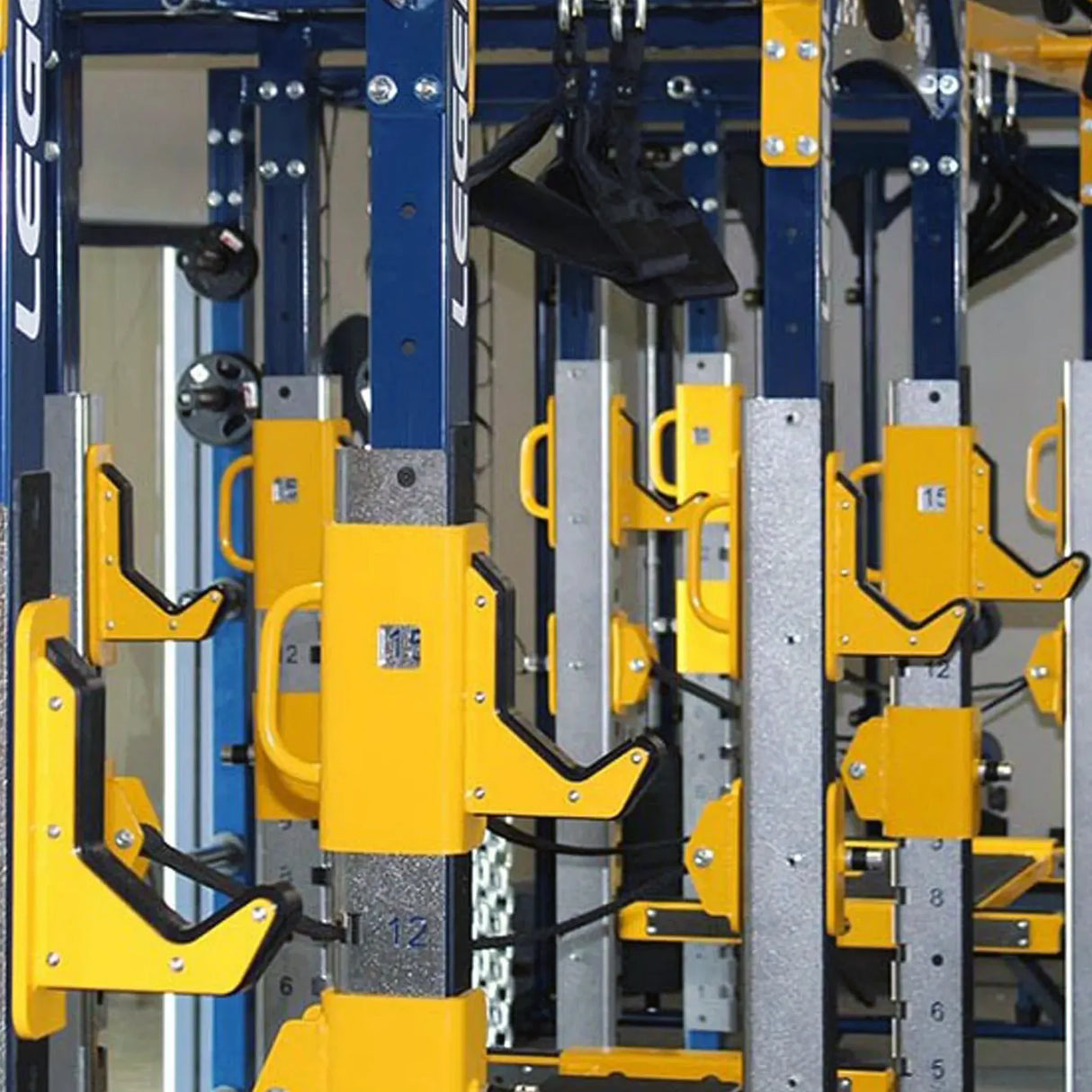Closeup of squat racks in a row highlighting the yellow barbell storage hooks