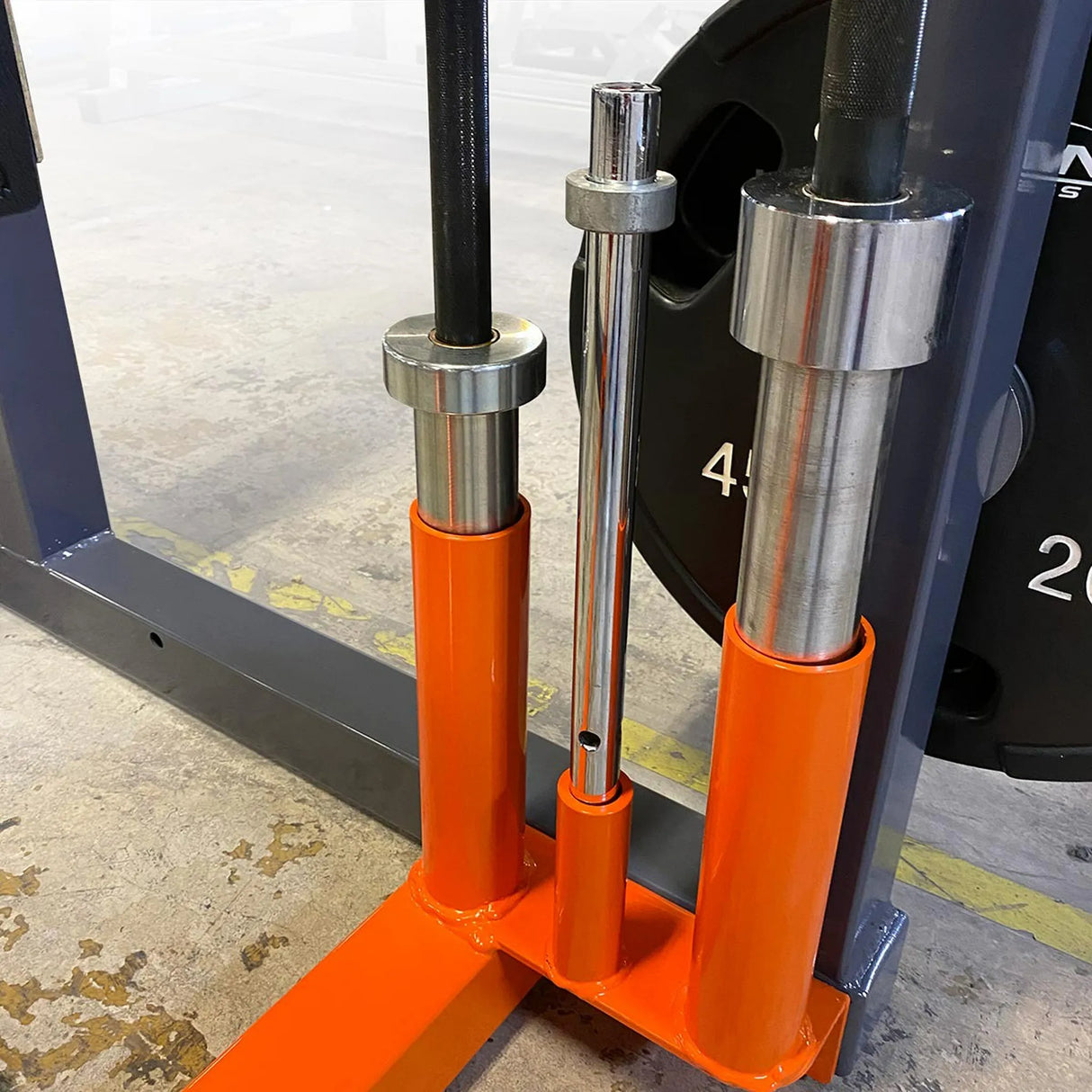 Close-up of orange metal barbell storage sleeves in a crossmember on a weightlifting rack