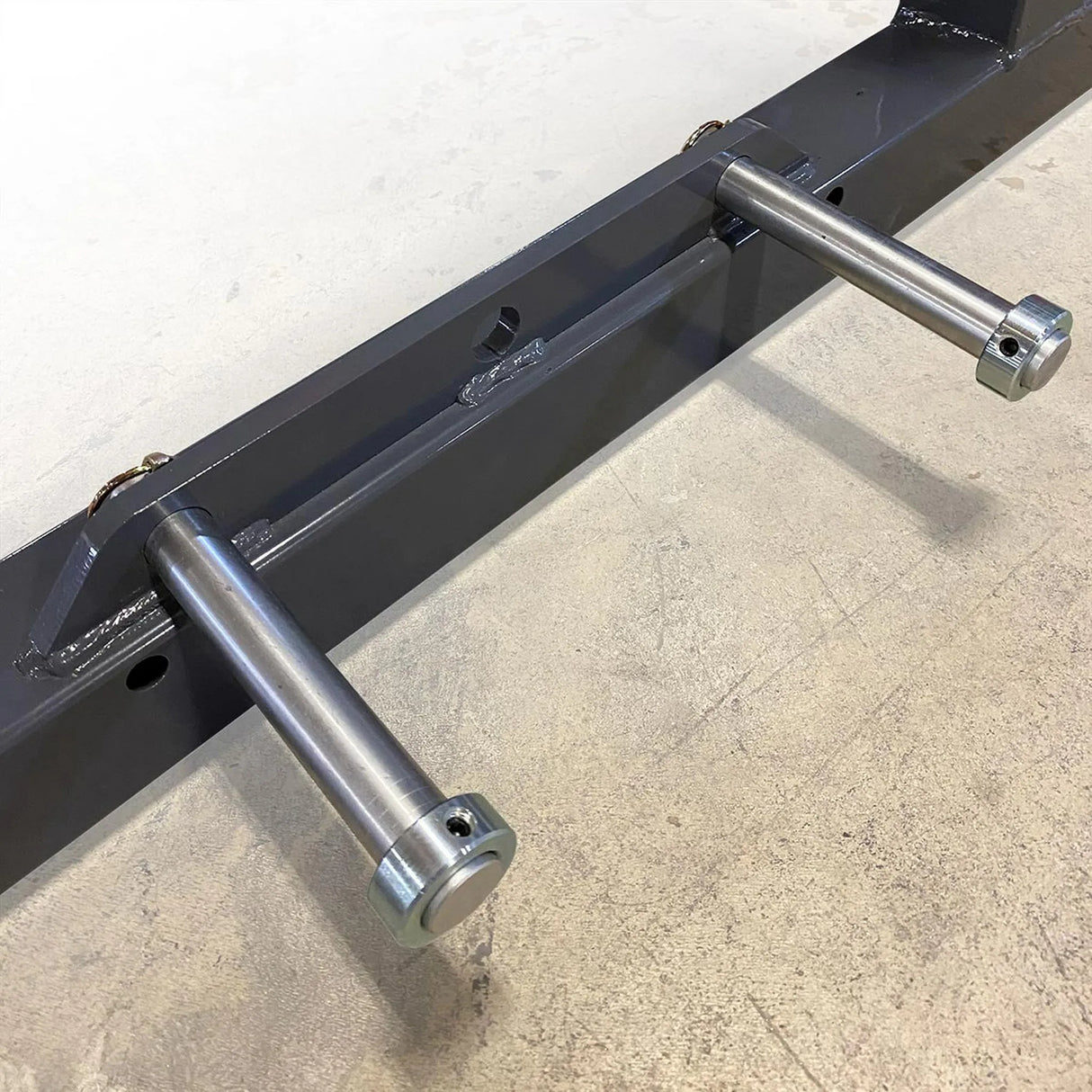 Metal bracket with two cylindrical metal rods on a concrete surface