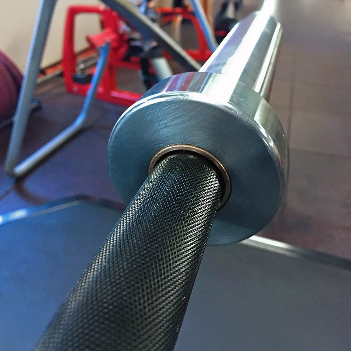 Close-up of a gym barbell with a blurred gym background