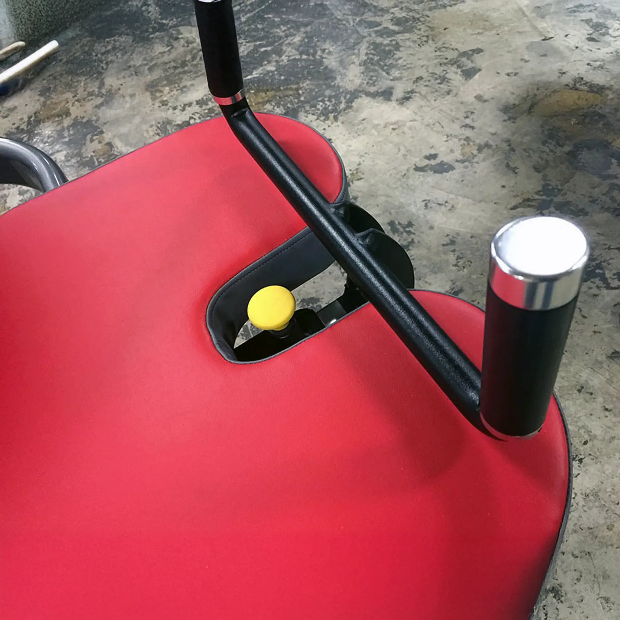 Red fitness machine pad with black handles with silver metal ends