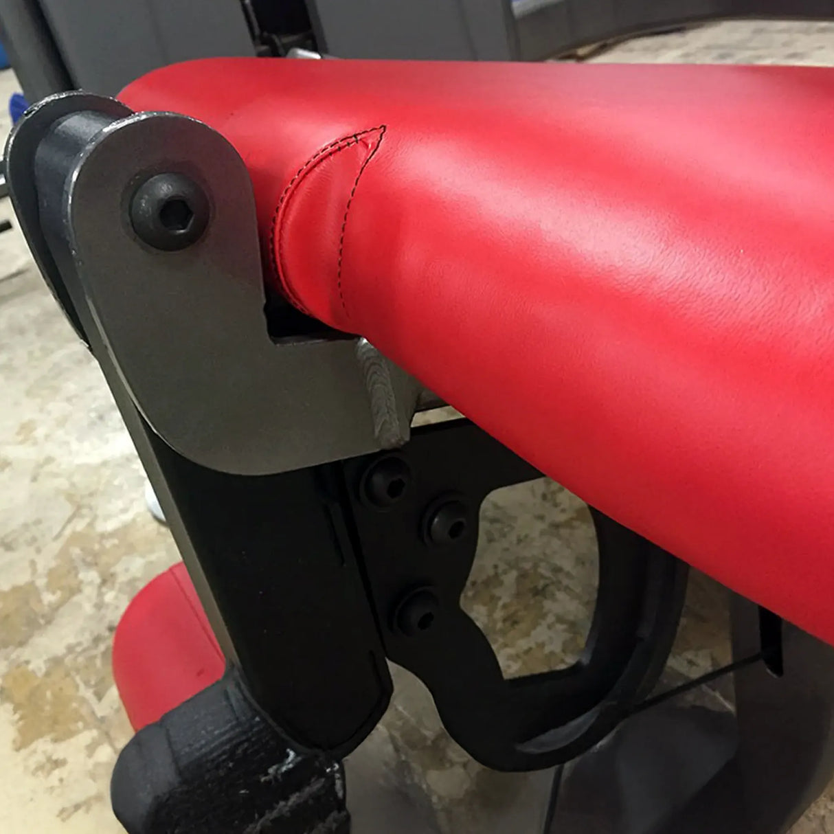 Close-up of a red exercise bench with red padding and metal frame.