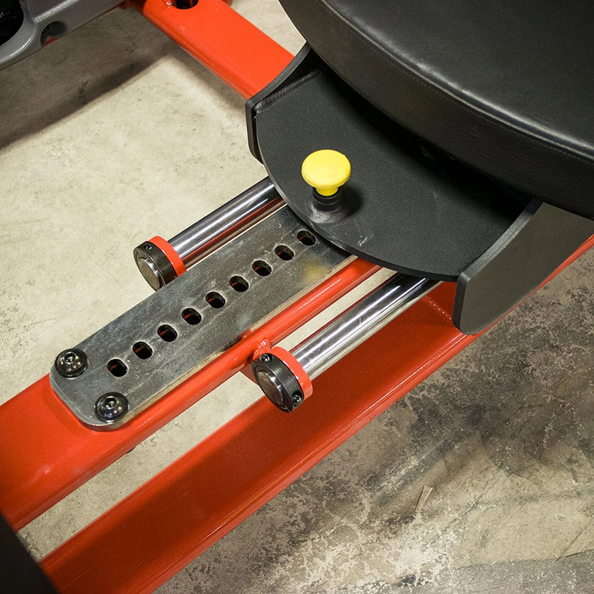 Close-up of a mechanical component with red and black colors on a concrete floor.