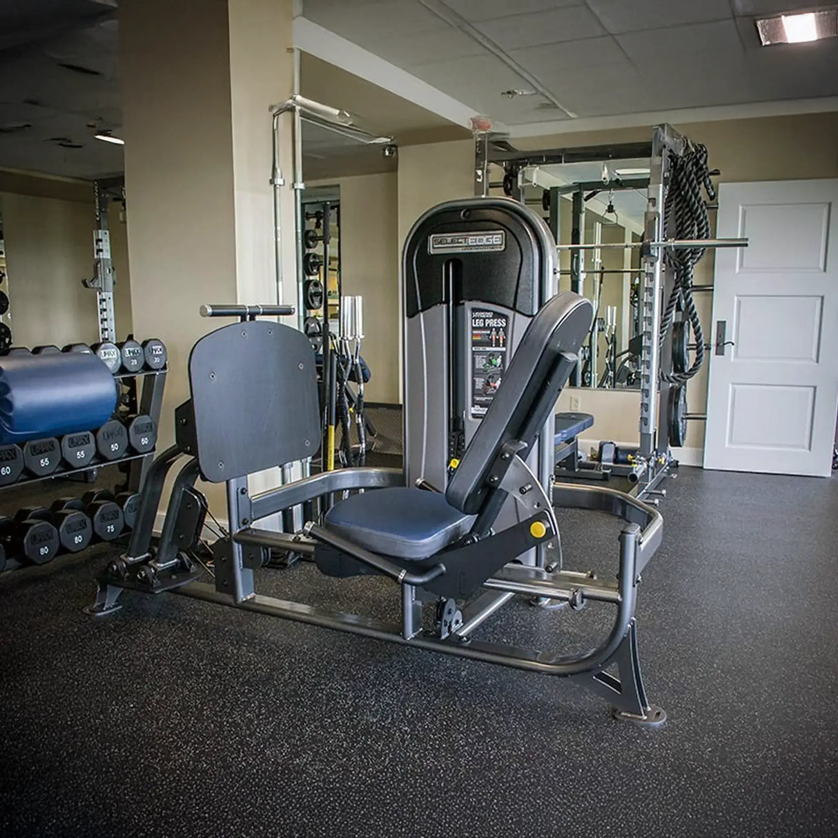 Gym machine in a fitness center with weights and mirrors in the background