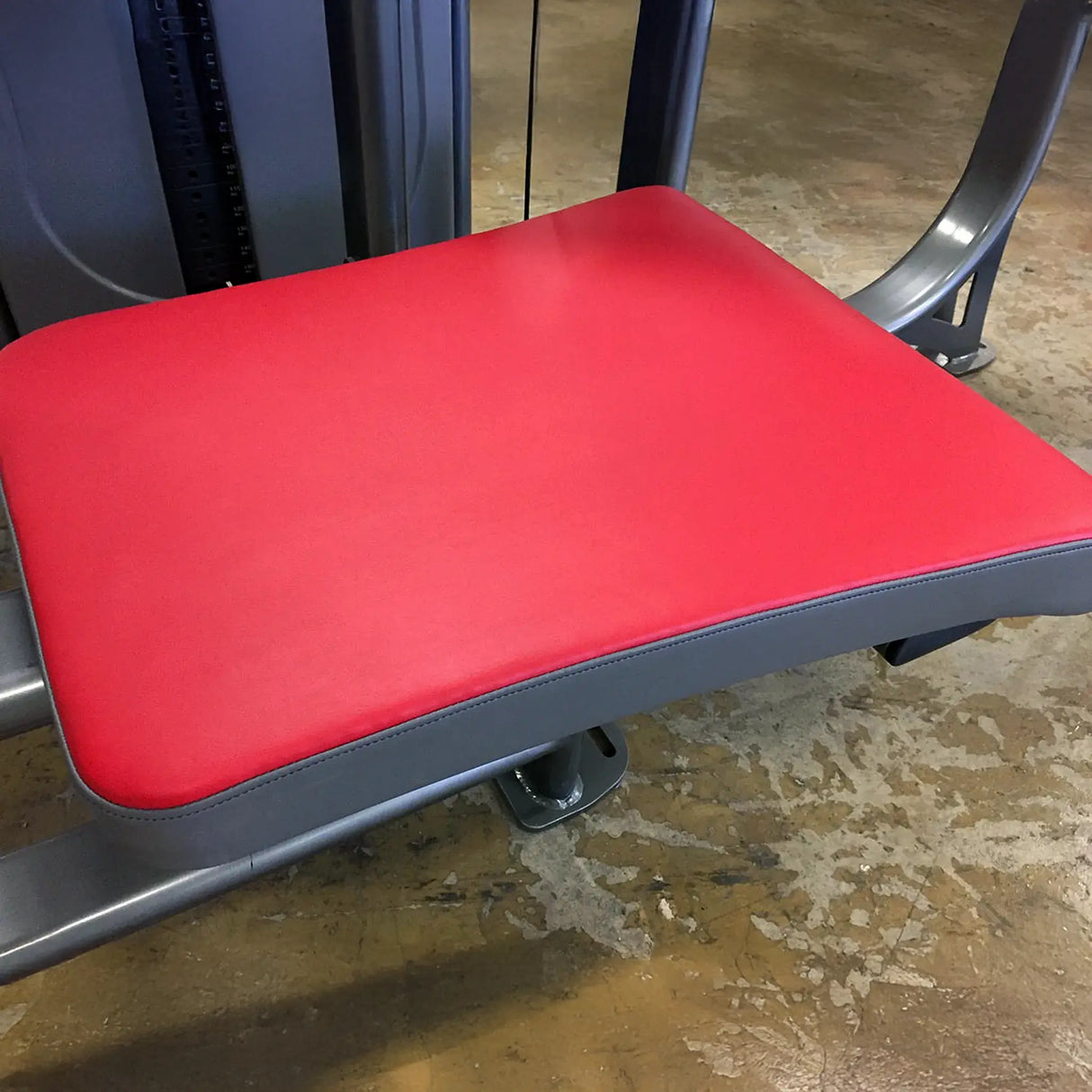 Red gym bench with gray frame on a concrete floor