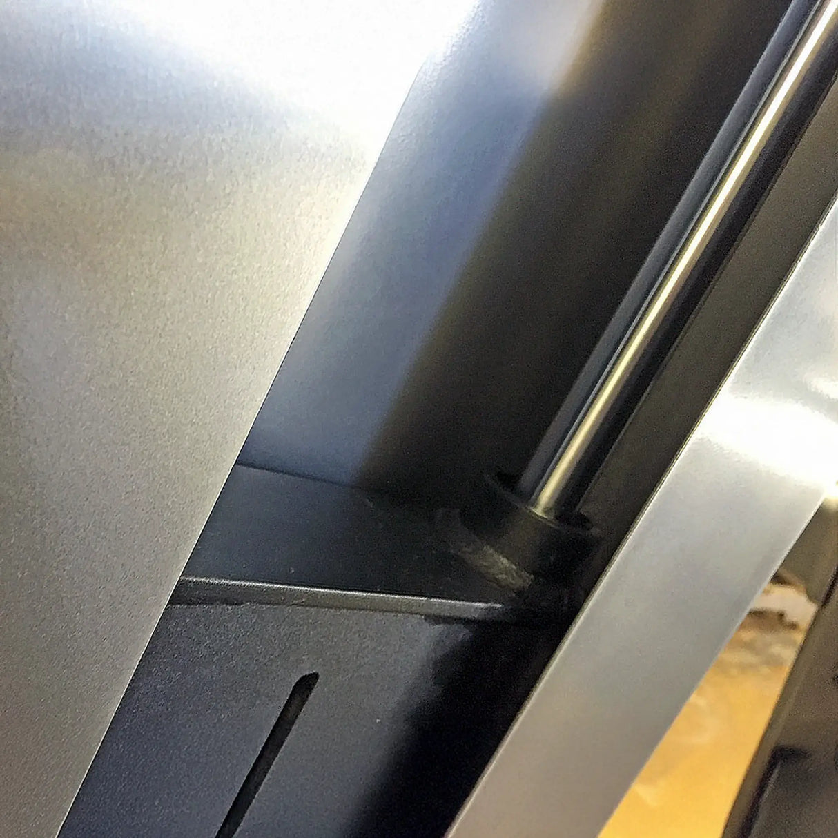 Close-up of a metallic object with a chrome guide rod and textured gray surface