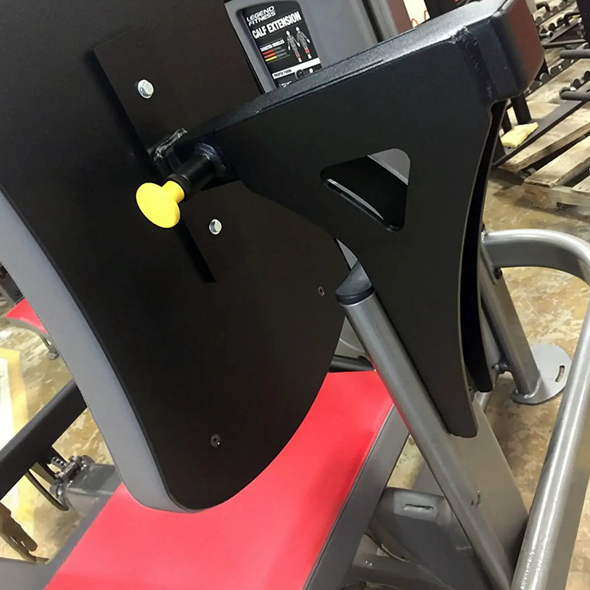 Close-up of a gym machine with a black, red, and gray metal seat