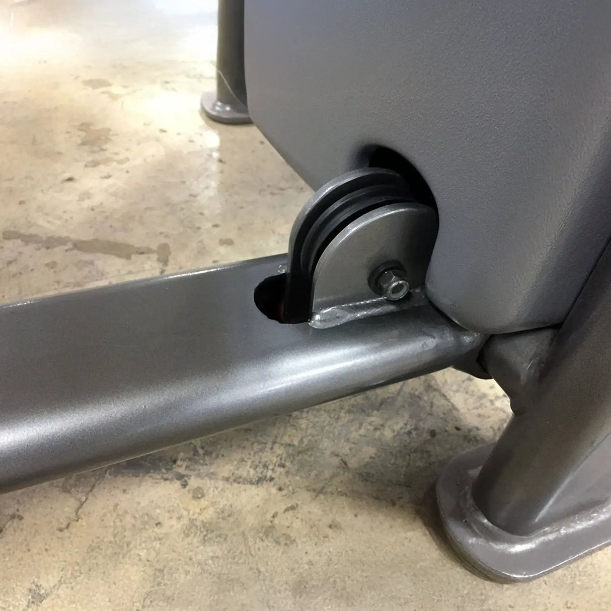 Closeup of gray metal components with a black pulley on a concrete floor