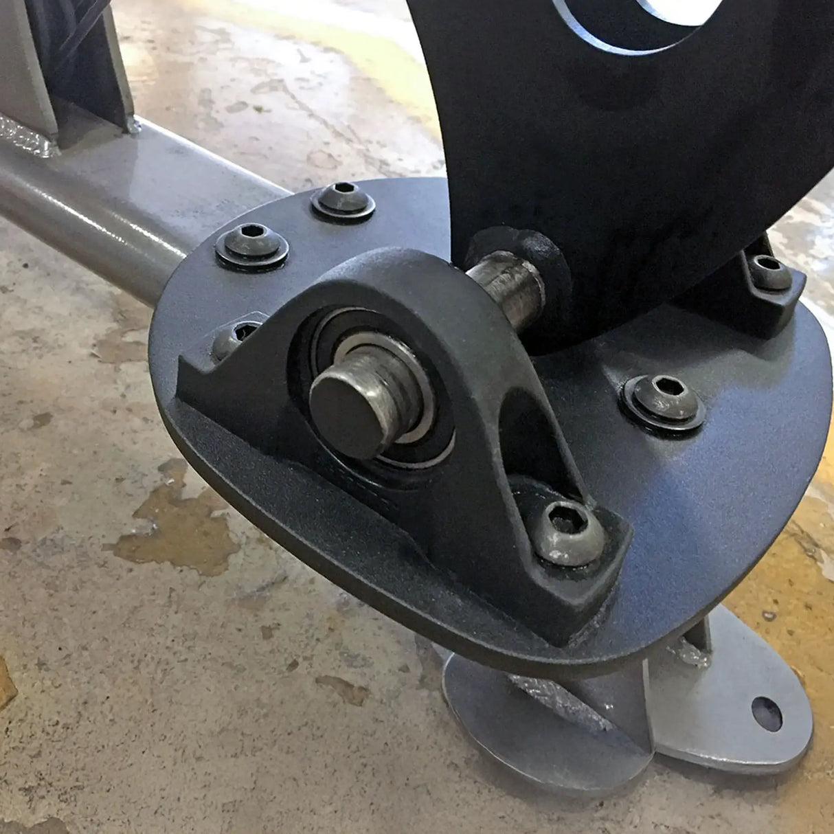 Close-up of a mechanical component with bolts on a concrete floor