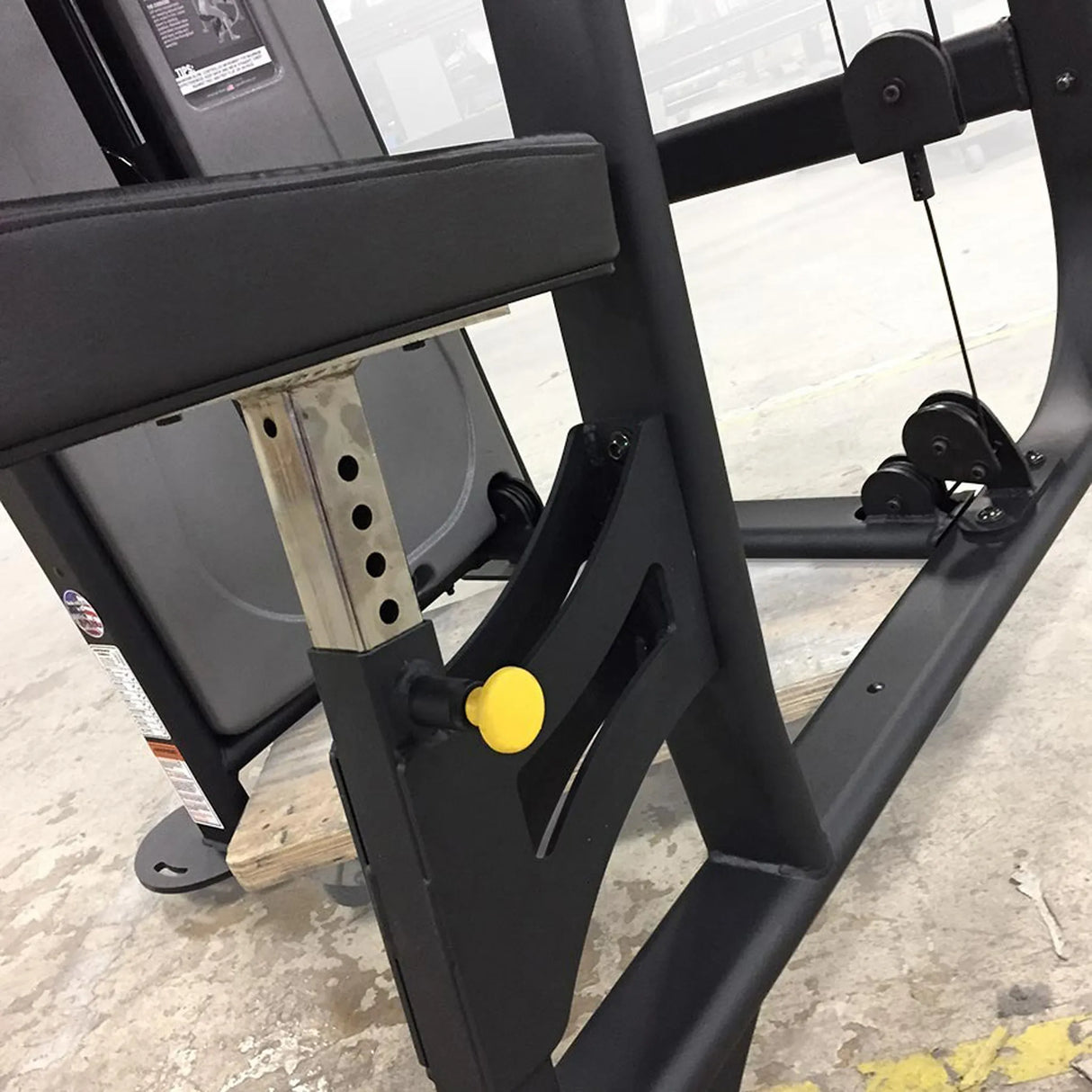 Close-up of a black metal frame with a yellow pop-pin on a concrete floor.